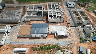 Luftaufnahme der im Bau befindlichen Wasseraufbereitungsanlage mit Betontanks, Filteranlagen und Servicegebäuden auf einem gerodeten Gelände.