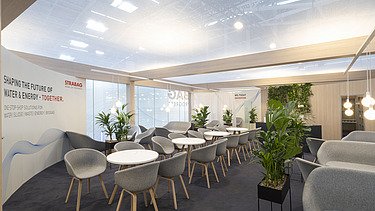 A dynamic perspective of the upper floor's glass facade featuring the STRABAG logo and hanging greenery.