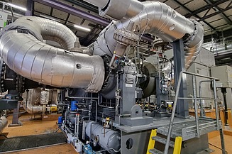 Eine industrielle Energieanlage mit großen isolierten Rohren und Maschinen, die für eine effiziente Energieerzeugung und Wärmerückgewinnung ausgelegt ist.