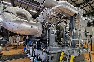 Eine industrielle Energieanlage mit großen isolierten Rohren und Maschinen, die für eine effiziente Energieerzeugung und Wärmerückgewinnung ausgelegt ist.