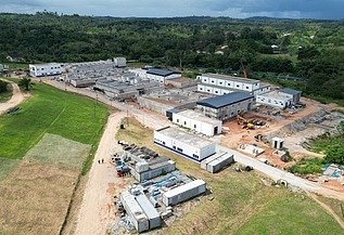 Aerial view of a large water treatment plant under construction, surrounded by green hills and open land.
