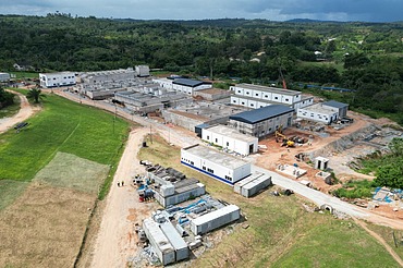 Aerial view of a large water treatment plant under construction, surrounded by green hills and open land.
